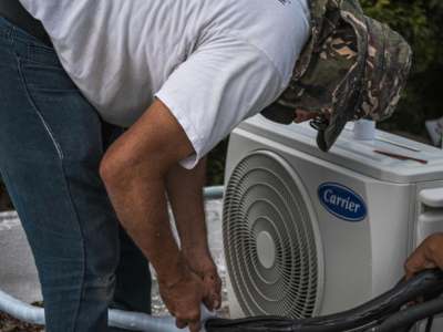 HVAC repair technician working on residential air conditioning equipment.