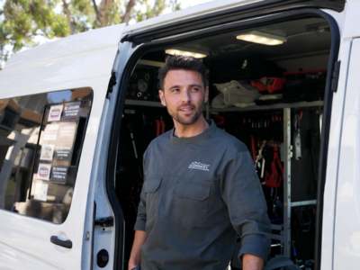 Professional HVAC technician standing next to a service van.