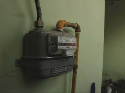 Gas meter with digital display mounted on pale green wall.