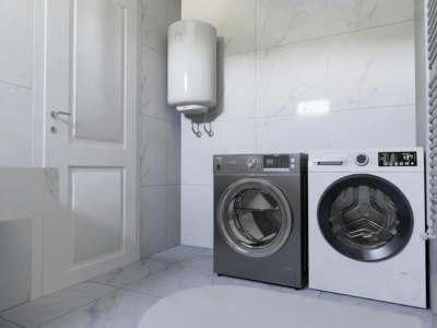 Modern laundry room with wall-mounted water heater above gray and white front-loading washing machines on marble-look tile flooring.