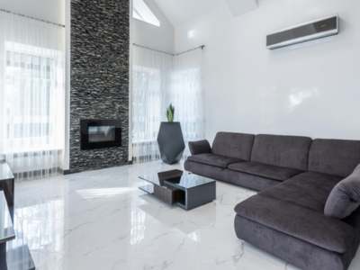Contemporary living room with stone fireplace, sectional sofa, and wall AC unit.