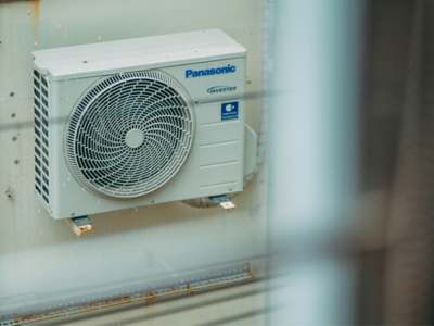 White Panasonic inverter air conditioning outdoor unit mounted on an exterior wall.