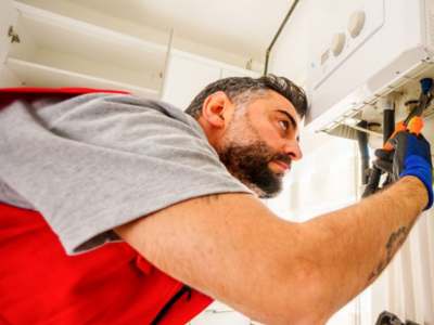 Professional plumber inspecting water heater installation.