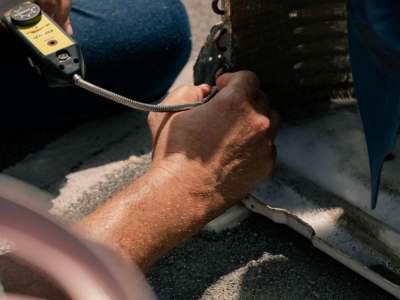 Close-up of an HVAC technician's hands working on an air conditioning component.