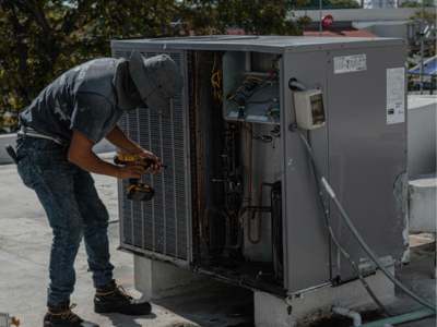 HVAC technician repairing outdoor air conditioning unit.